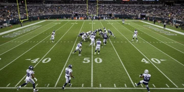 Dynamic NFL game action under stadium lights, illustrating rule change impact.