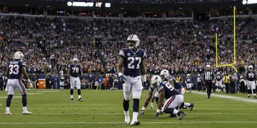 A player on the sidelines during a tense 2024 NFL playoff game, observing the action intently, symbolizing unseen stories.