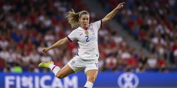 USWNT player striking a soccer ball on a stadium field