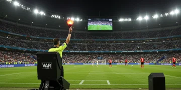 Referee signaling VAR review on a soccer field during a professional match.